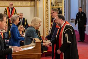 鶹ý Vice-Chancellor and Professor receiving medal and scroll from the Royal Family in Buckingham Palace